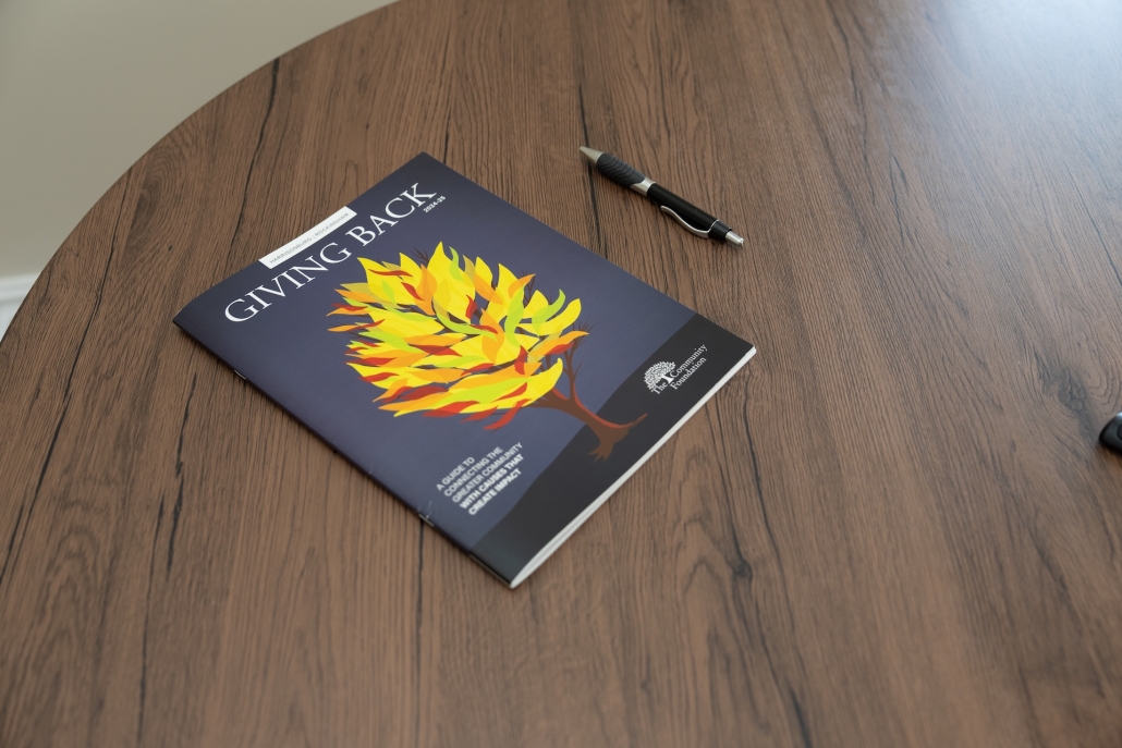 TCF's Giving Back Guide on a table with a pen.